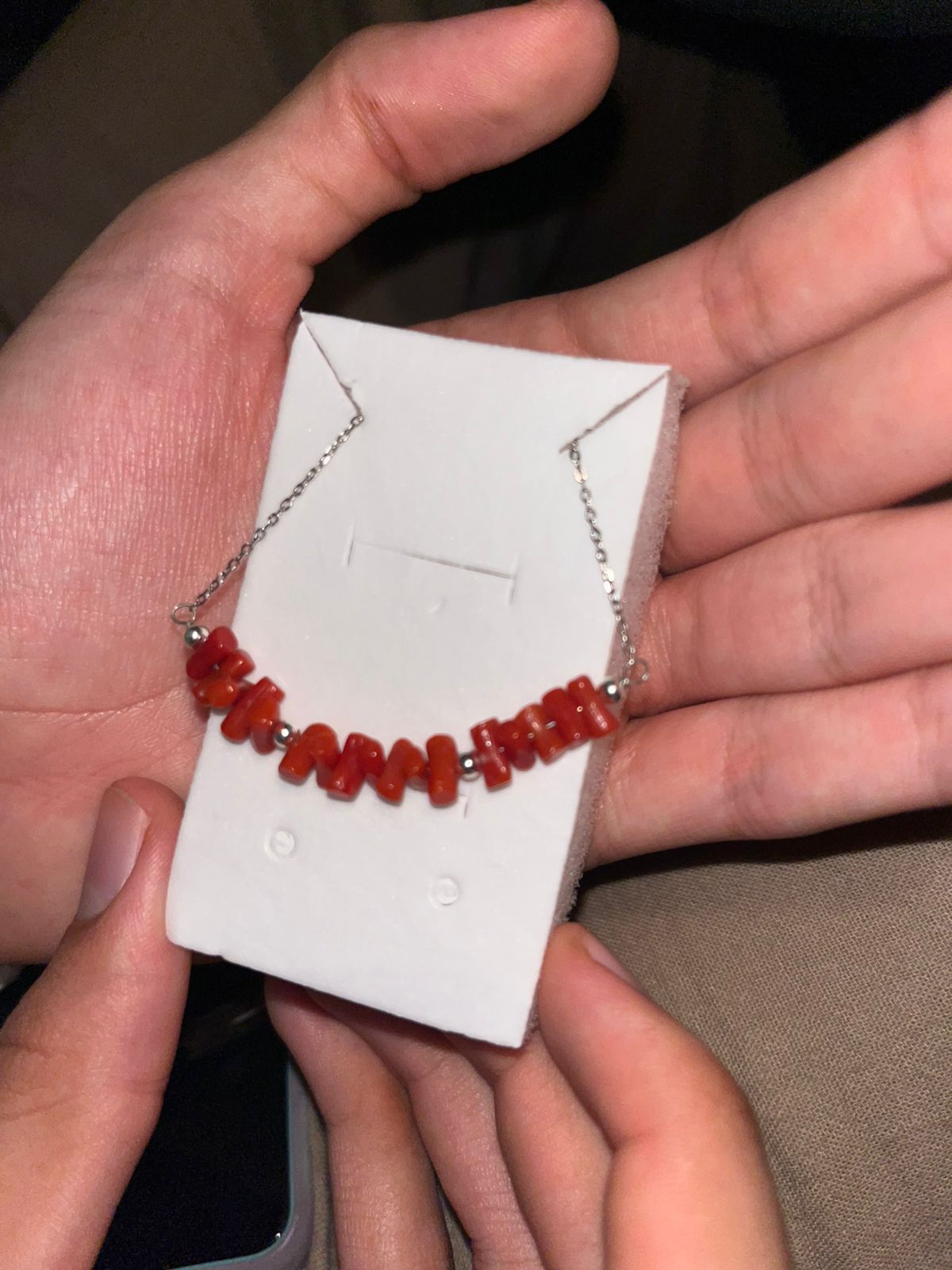 Mains d'un artisan marocain façonnant un collier en corail naturel à Casablanca