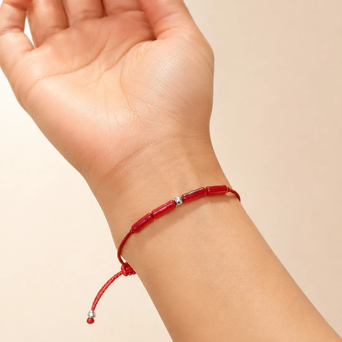 Bracelet Talia porté au poignet — cordon rouge et corail naturel AMAYAS